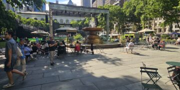Bryant Park NYC fountain and main plaza with Parisian chairs and Manhattan skyline