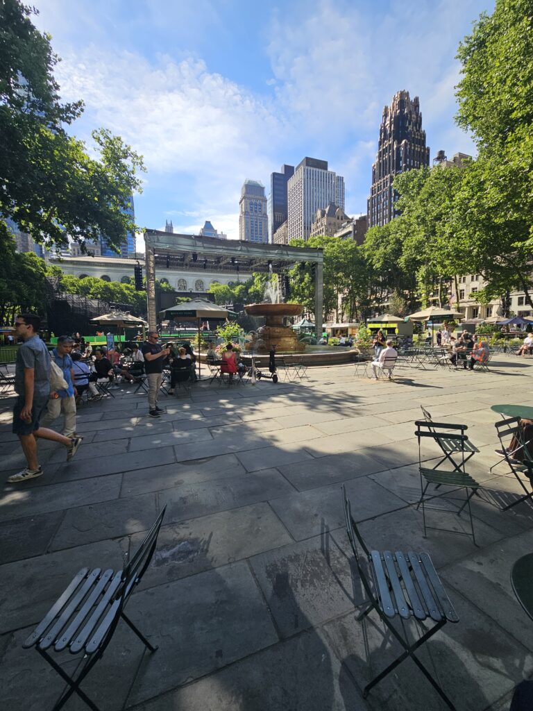 Bryant Park NYC fountain and main plaza with Parisian chairs and Manhattan skyline