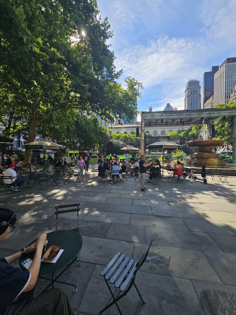 Bryant Park NYC wide view showing fountain New York Public Library building and Manhattan skyline