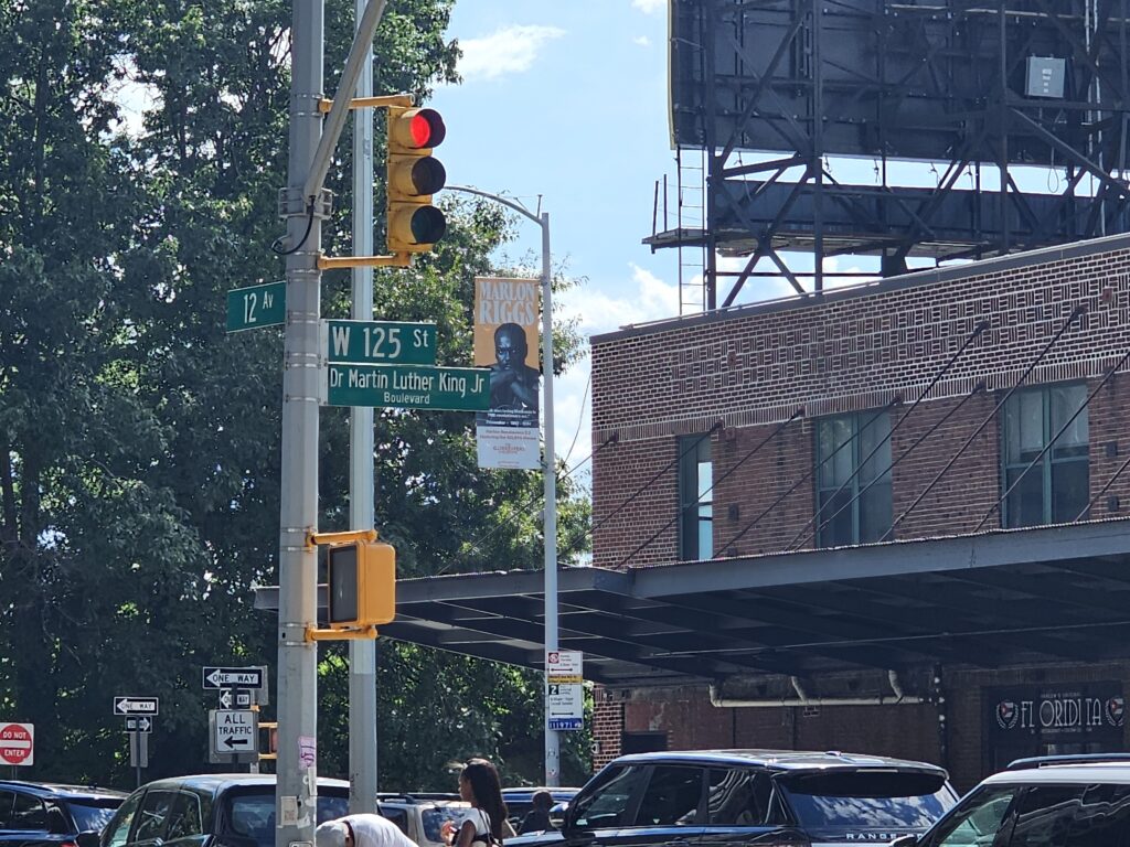 West 125th Street and 12th Avenue street sign Harlem NYC with Marlon Riggs banner