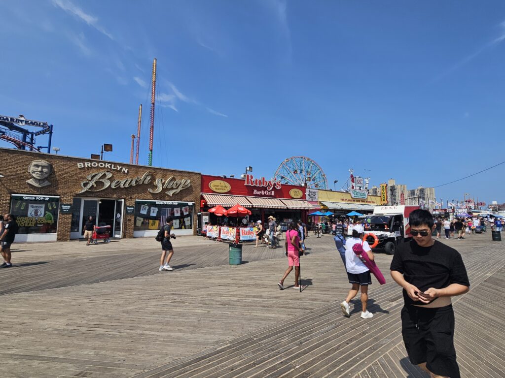 Visitors strolling the Coney Island boardwalk near local shops