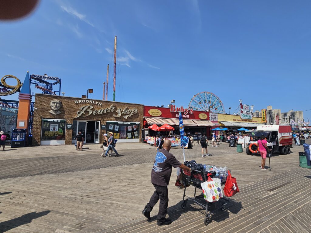 A vendor pushing a cart along Coney Island boardwalk near Brooklyn Beer Co.