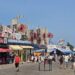 Coney Island NYC guide: boardwalk with amusement rides and city skyline