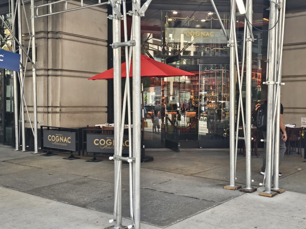Entrance of Brasserie Cognac Américain with red umbrella and signage