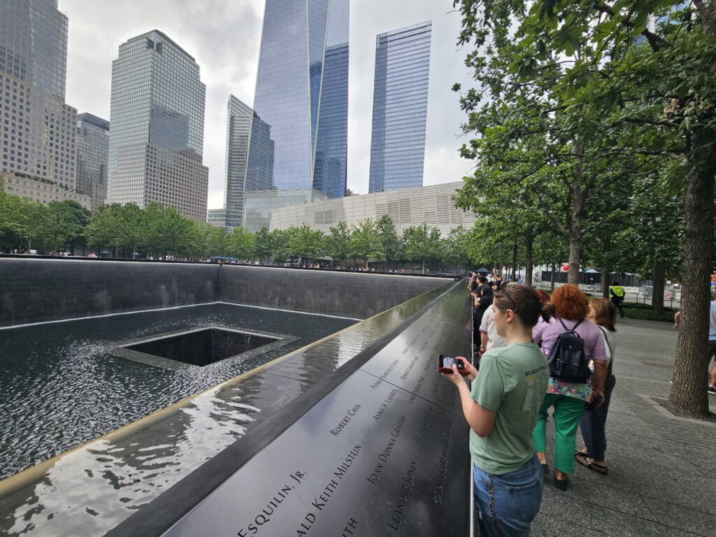 Visitors at the National September 11 Memorial bronze name parapets NYC