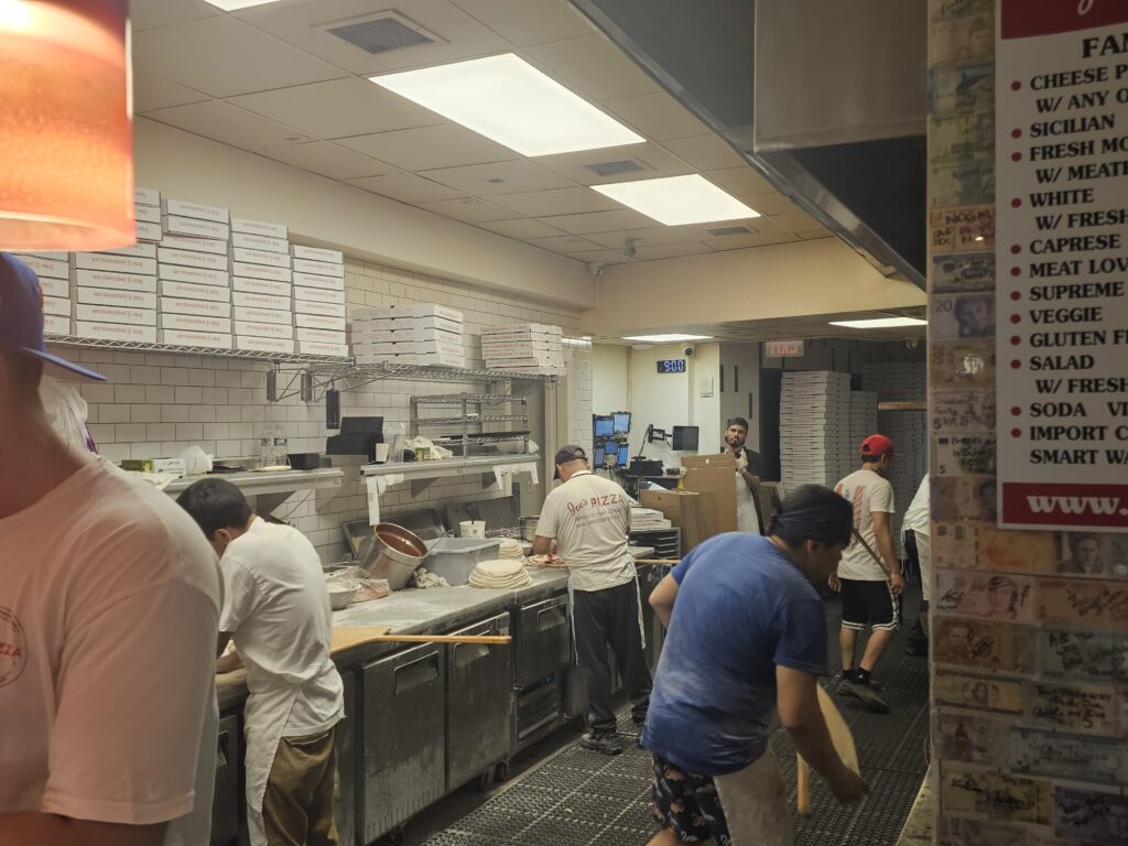 Joe's Pizza kitchen staff preparing pizzas behind the counter