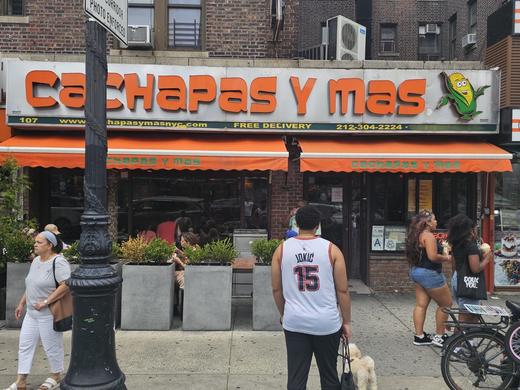 : Cachapas y Mas NYC storefront sign with orange and green awning in Inwood, Manhattan