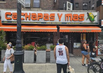 : Cachapas y Mas NYC storefront sign with orange and green awning in Inwood, Manhattan