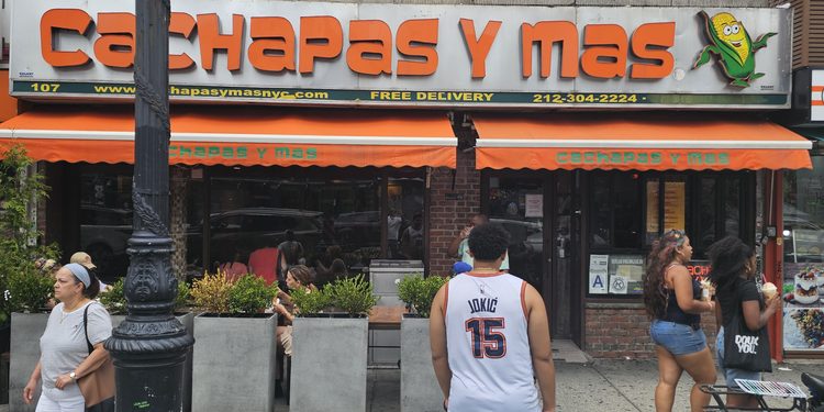 : Cachapas y Mas NYC storefront sign with orange and green awning in Inwood, Manhattan