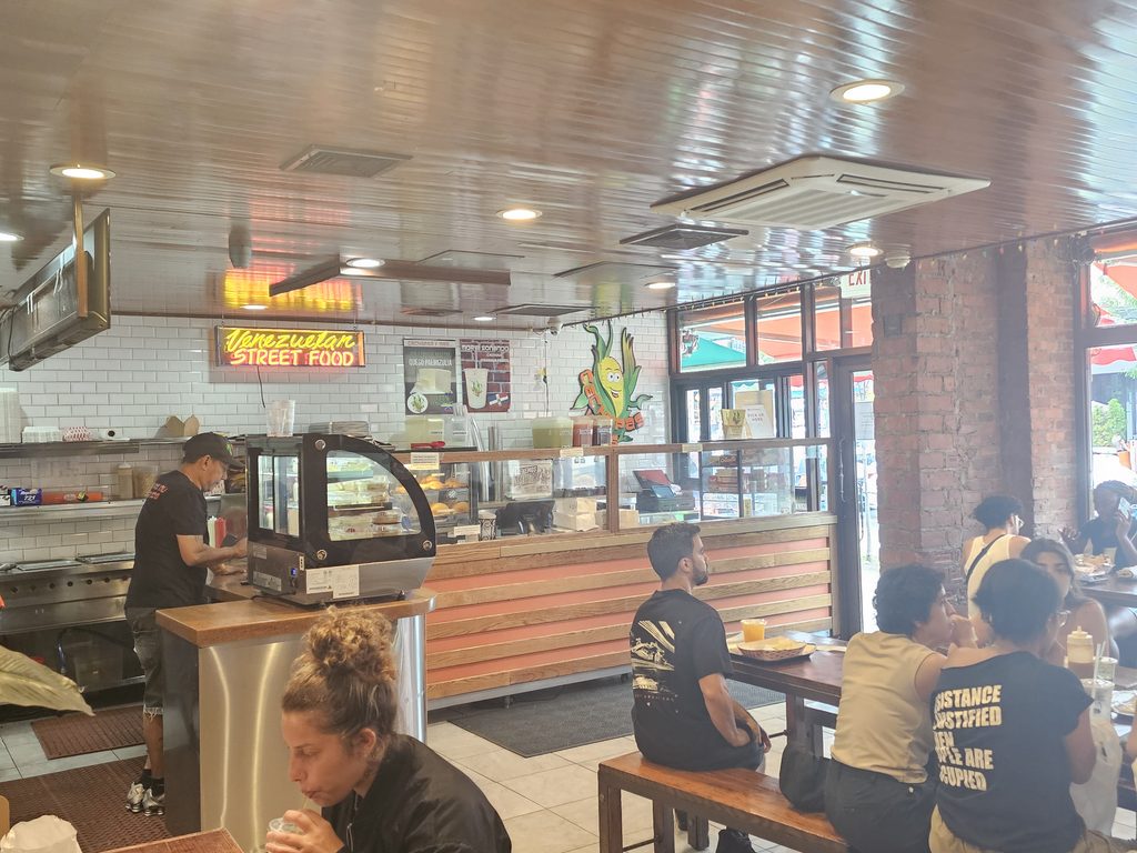 Counter and open kitchen area at Cachapas y Mas NYC with Venezuelan street food signage