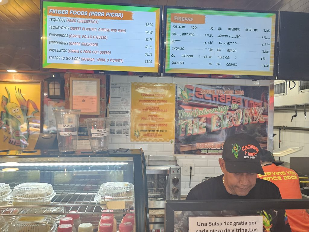 Menu board listing cachapas, arepas, tequeños, and patacones at Cachapas y Mas NYC
