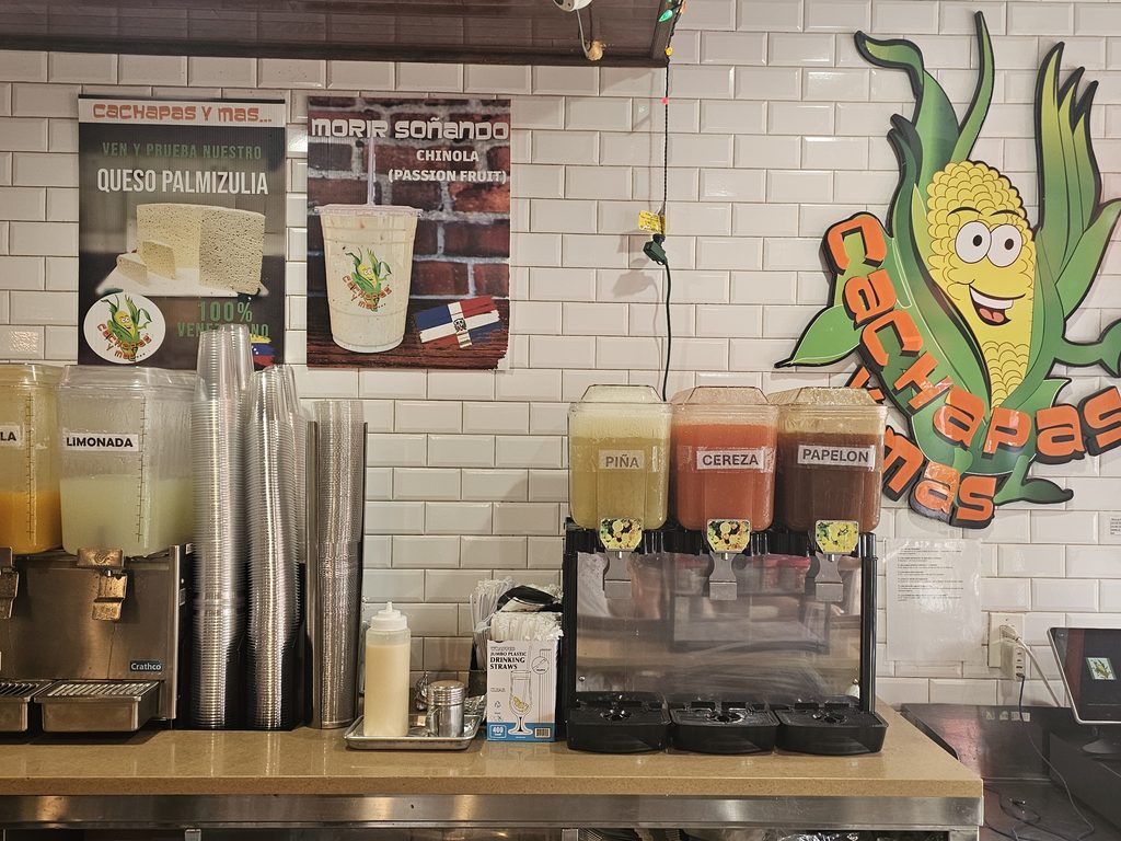 Cachapas y Mas corn mascot artwork and fresh juice dispensers inside the Inwood location