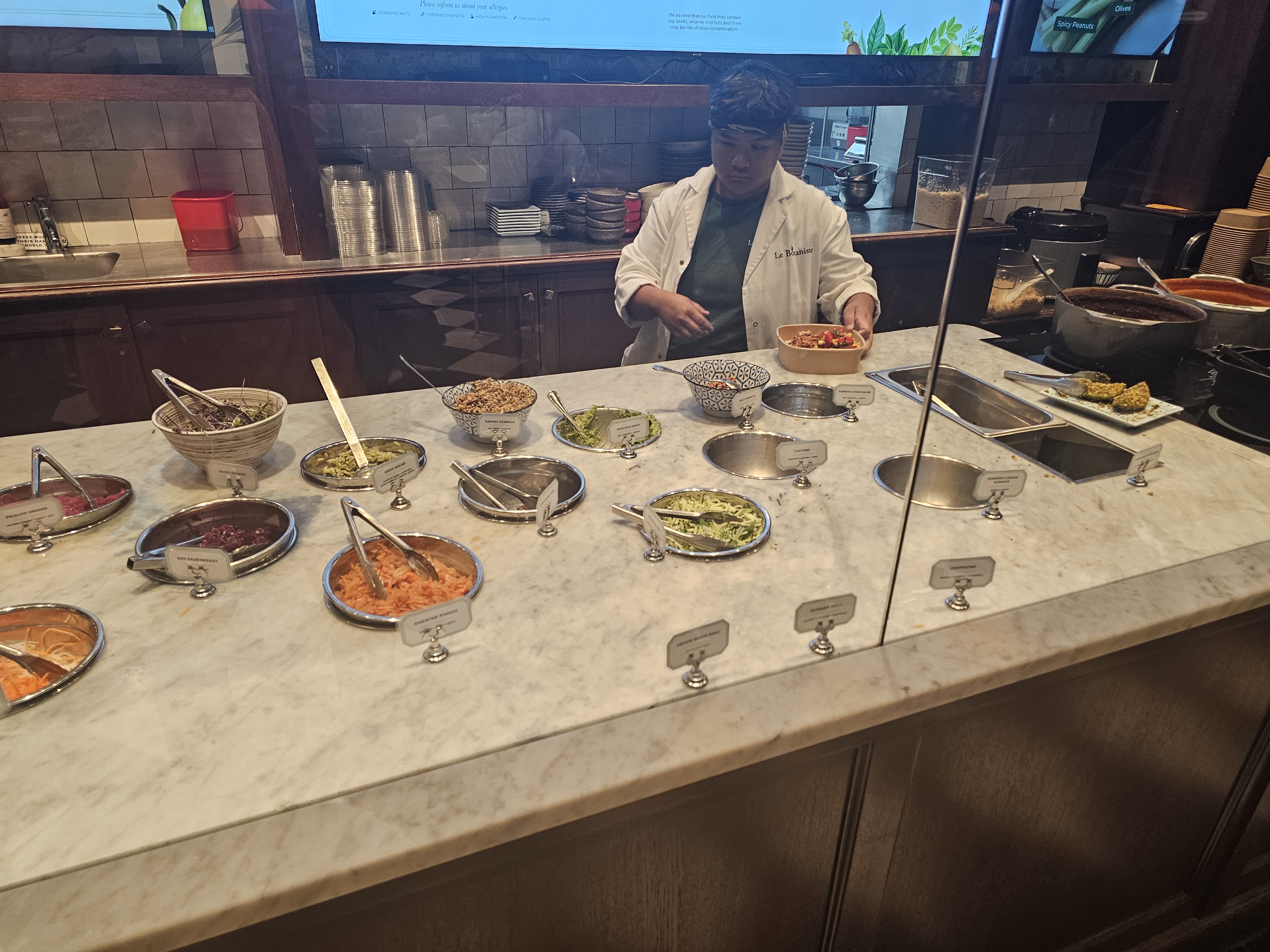 Staff member preparing bowls at the veggie bar inside Le Botaniste Bryant Park