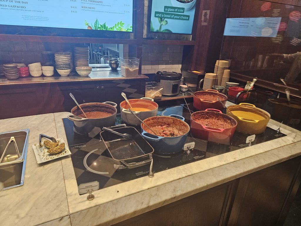 Colorful Dutch ovens of prepared bowls on the marble veggie bar at Le Botaniste Bryant Park