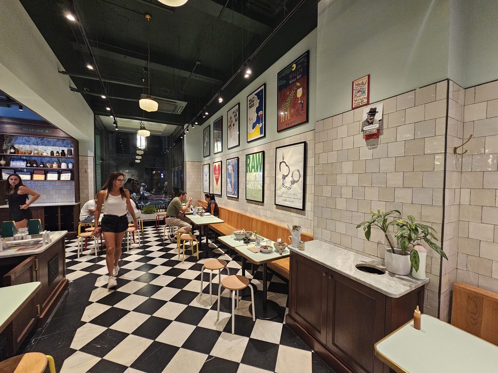 Back dining room with checkered floor and framed wall art at Le Botaniste Bryant Park