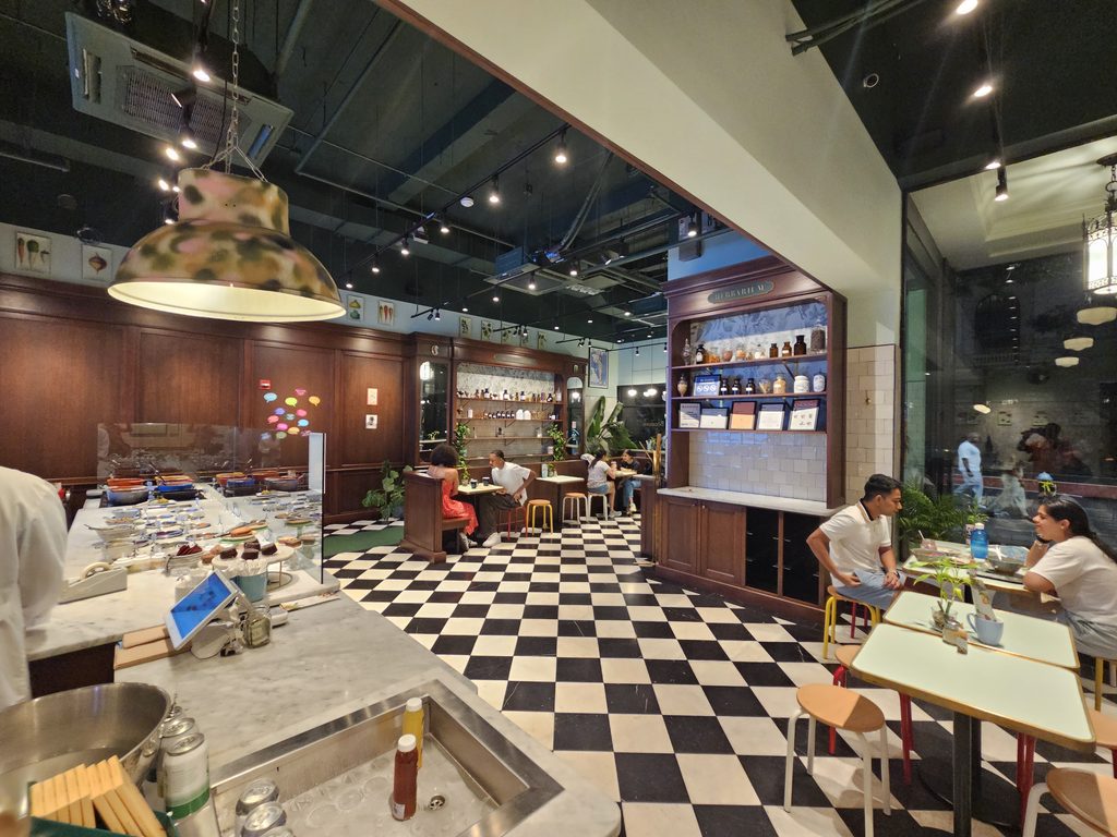 Interior dining room at Le Botaniste Bryant Park with checkered floor and apothecary shelving
