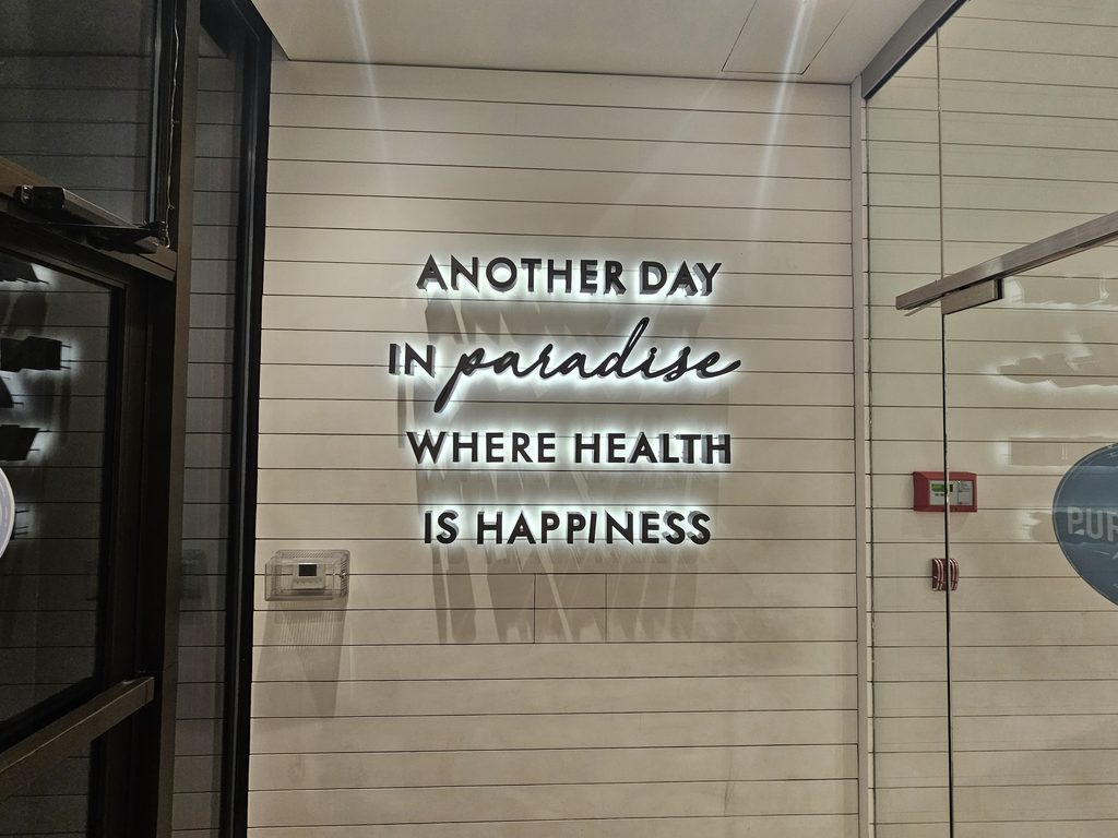 Another Day in Paradise, Where Health Is Happiness" wellness wall art inside Pura Vida Miami NYC