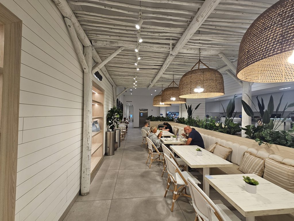 Dining room at Pura Vida Miami NYC with wood-beam ceiling and woven pendant lights