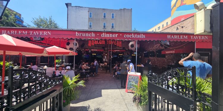 Harlem Tavern NYC entrance patio with red awnings and outdoor seating