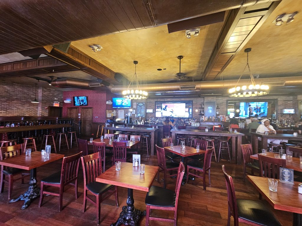 Indoor sports bar seating area at Harlem Tavern NYC with multiple TV screens and chandeliers