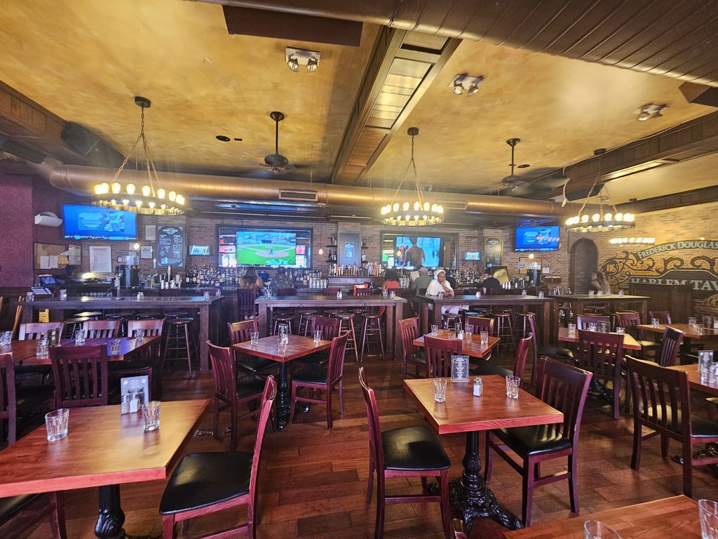 Interior wall signage reading Frederick Douglass Boulevard and Harlem Tavern inside the sports bar