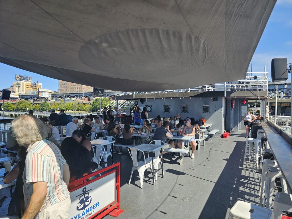 Deck view of Baylander Steel Beach showing the ship's portholes and the Manhattan skyline