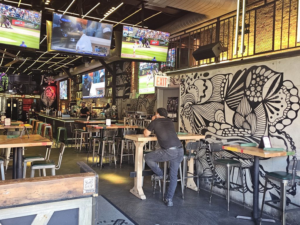 Brick-walled dining area at El Jefe Sports Cantina with neon signage and sports on TV