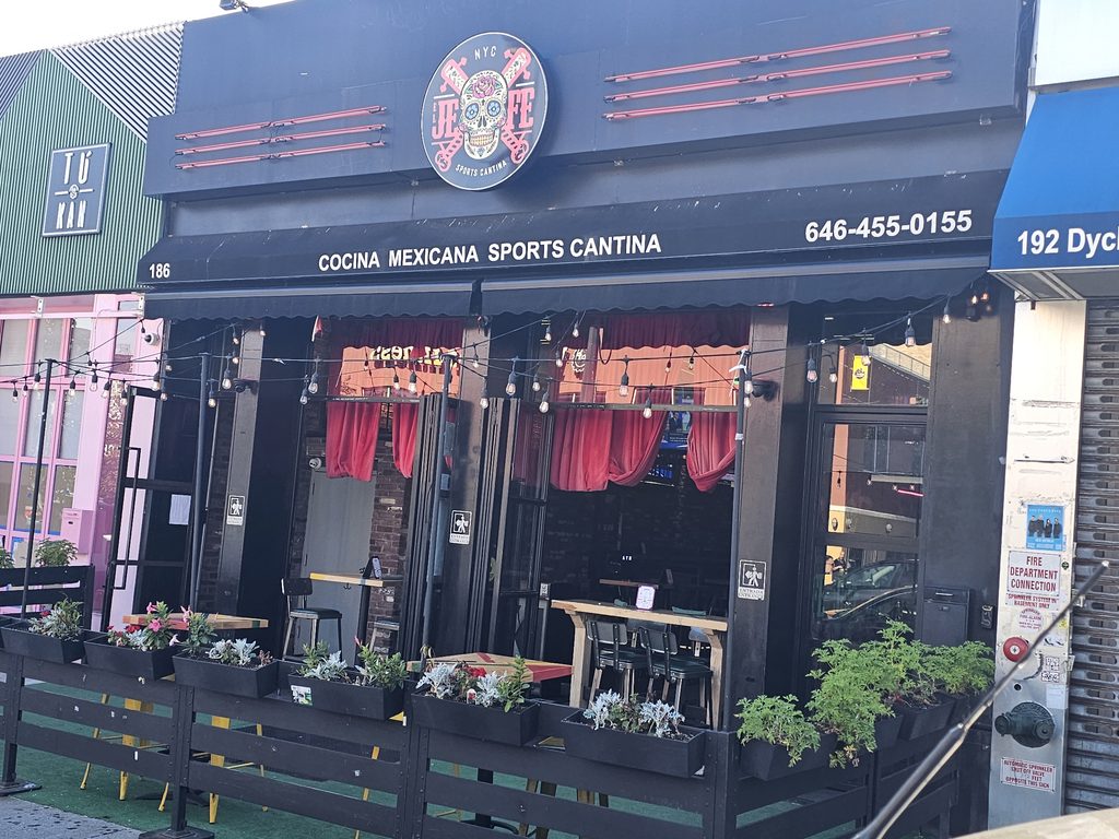 Daytime exterior of El Jefe Sports Cantina with string lights and sidewalk patio seating