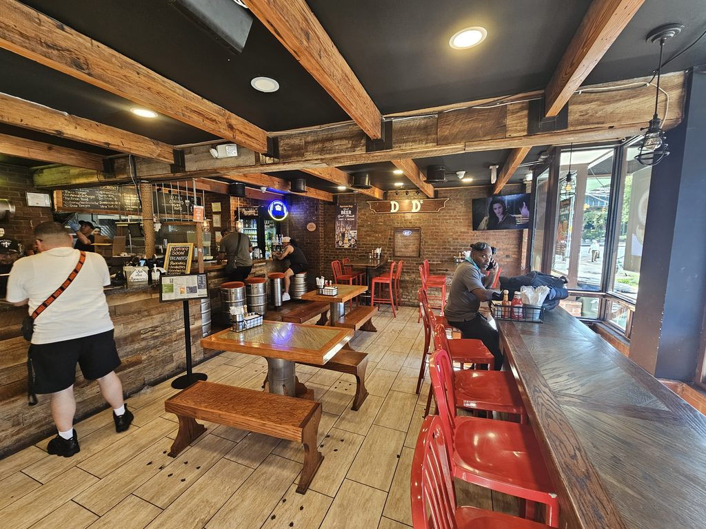 Dyckman Dogs NYC interior with keg barstools and exposed wood-beam ceiling