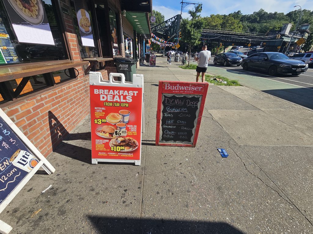 Sidewalk sign outside Dyckman Dogs NYC on Dyckman Street in Inwood