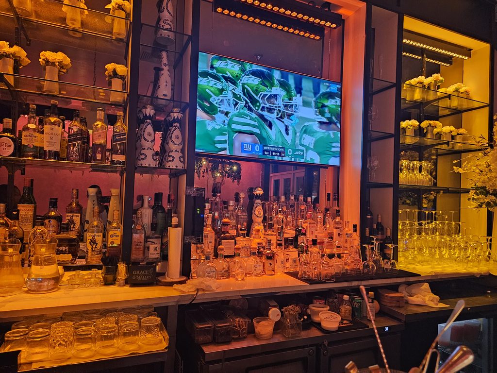 Aroma Restaurant Bar cocktail bar with bottles and a mounted TV screen