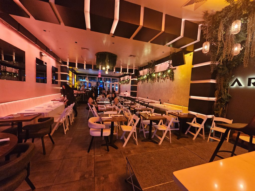 Aroma Restaurant Bar seating area with white folding chairs and hanging plants