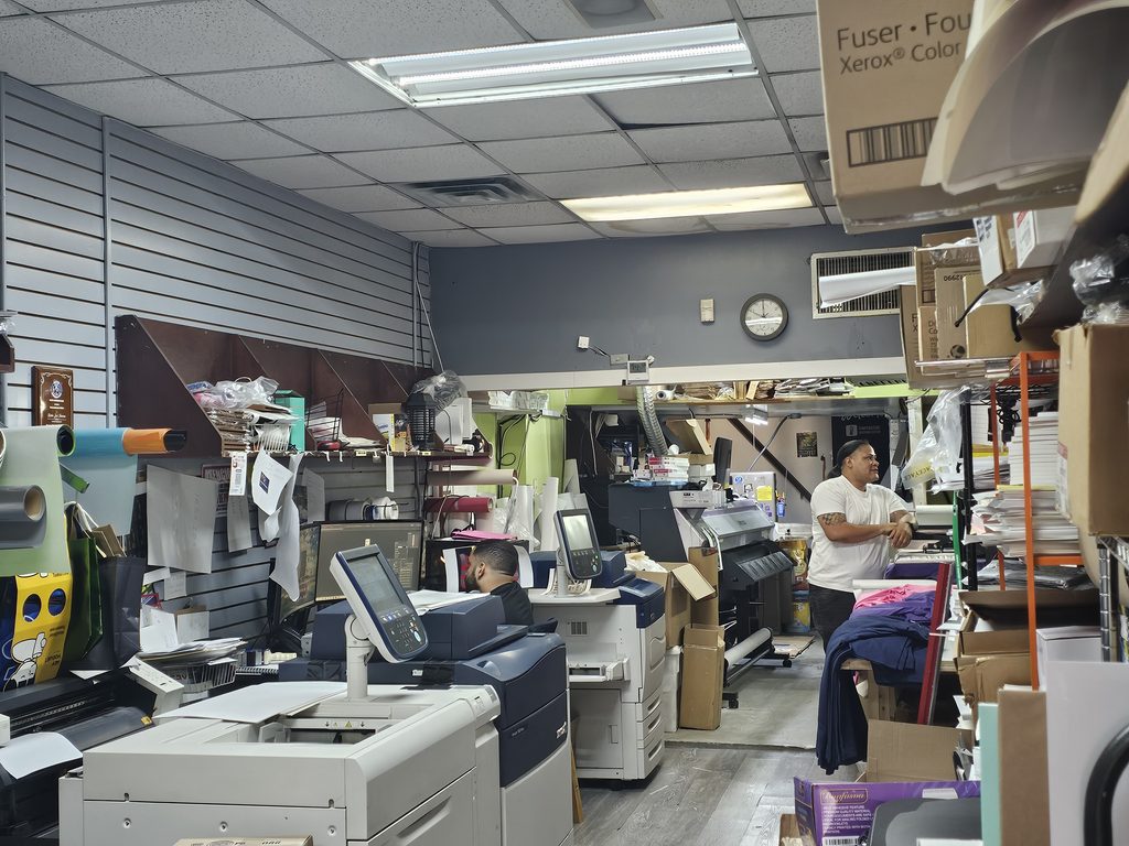 Staff operating a large-format printer at Lino Press NY print shop