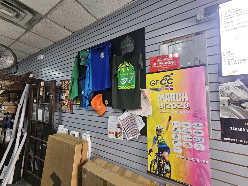 Sample T-shirts, caps, and event banners displayed on the wall at Lino Press NY