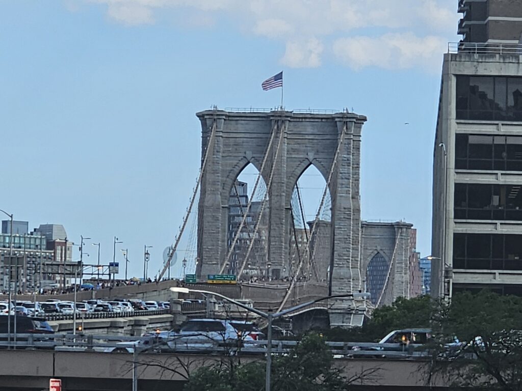 Brooklyn Bridge Gothic stone towers viewed from below, with traffic and skyline