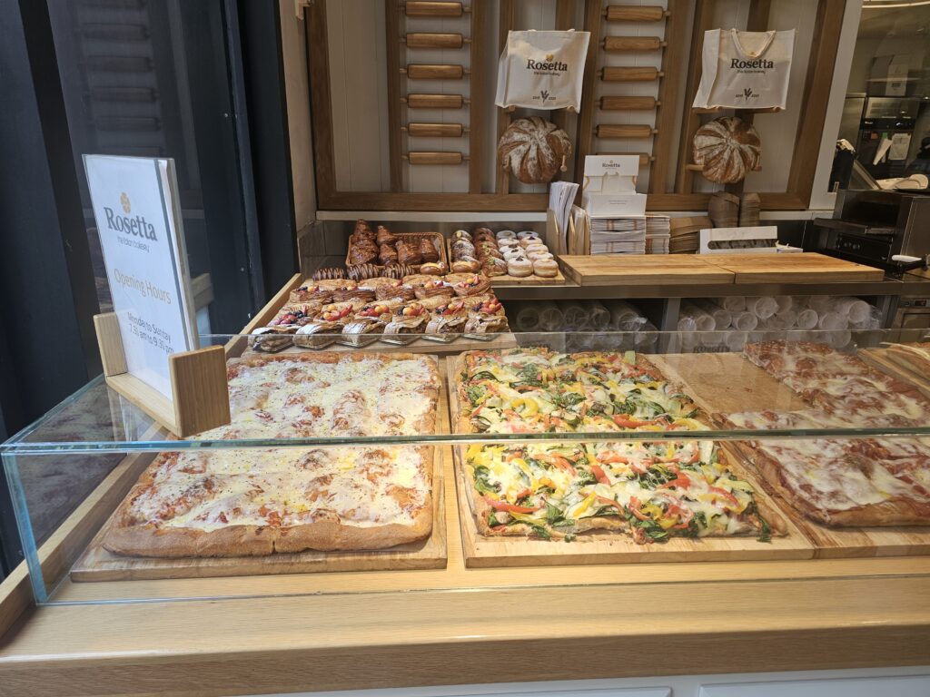 Rosetta Bakery pizza and focaccia display case with opening hours sign