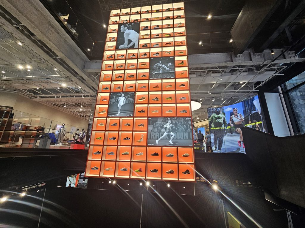 Glowing orange LED sneaker wall rising through the atrium inside Nike House of Innovation NYC