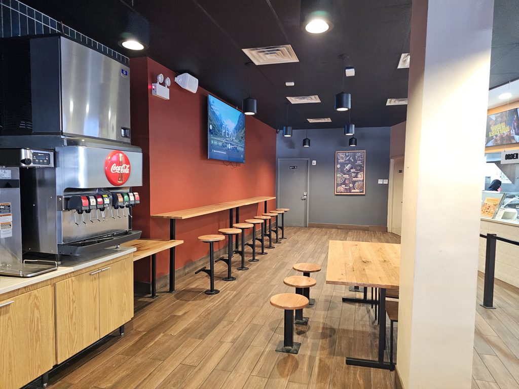 Indoor seating area and drink station at QDOBA Fordham Road in the Bronx