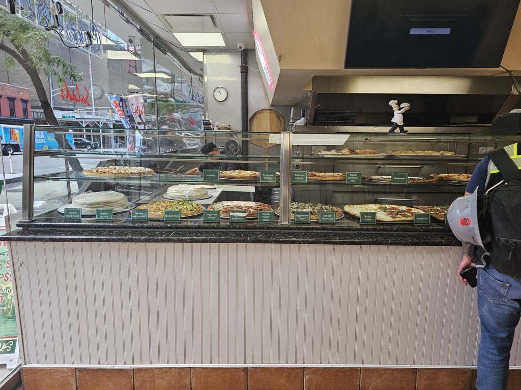 Pizza counter and prepared food display inside Cassiano’s Pizza NYC