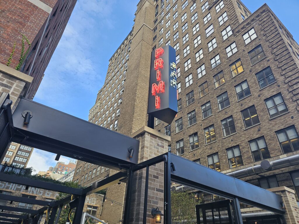 Bar Primi Penn District exterior with PRIMI sign and Midtown buildings