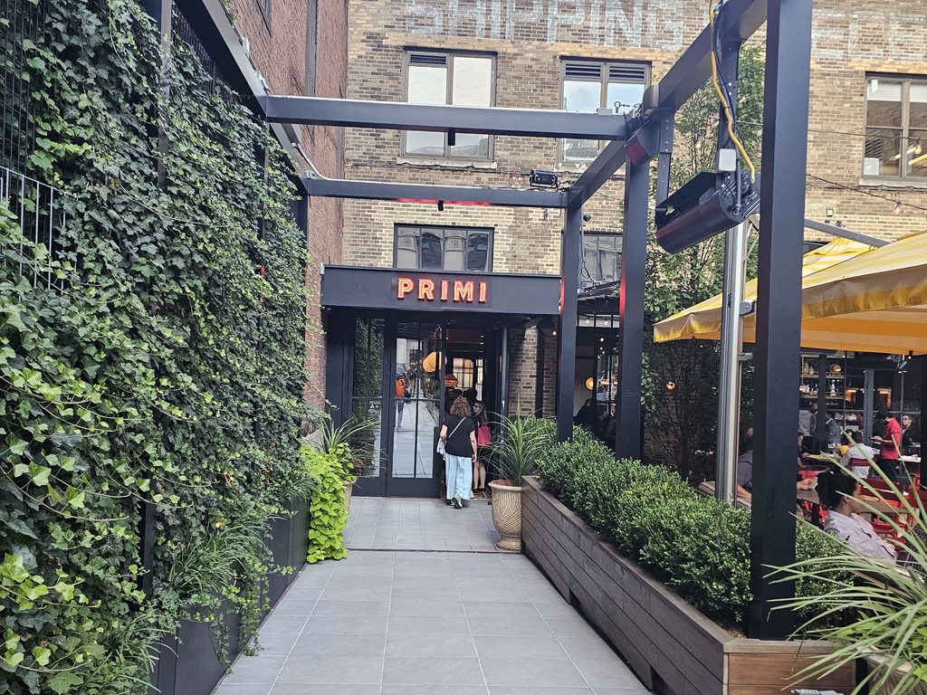 Busy Bar Primi Penn District patio with outdoor diners and yellow umbrellas
